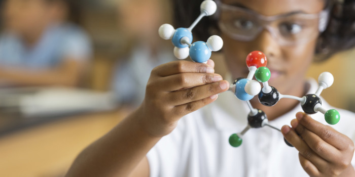 A young child is playing with a molecular model in a science class