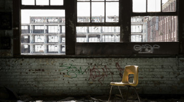 A plastic chair sits in the window light of an abandoned school in Chicago