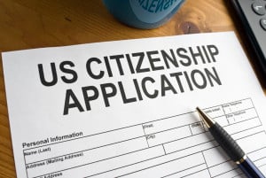 A piece of paper reads "US Citizenship Application" on a desk with a pen