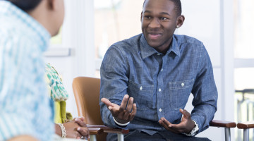 A group of people talking to one another, in an academic or professional environment, looking like they're engaged