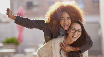 Two friends happily roam through the streets together, on piggy back