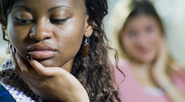 One person in the foreground is sad, while another in the background is talking