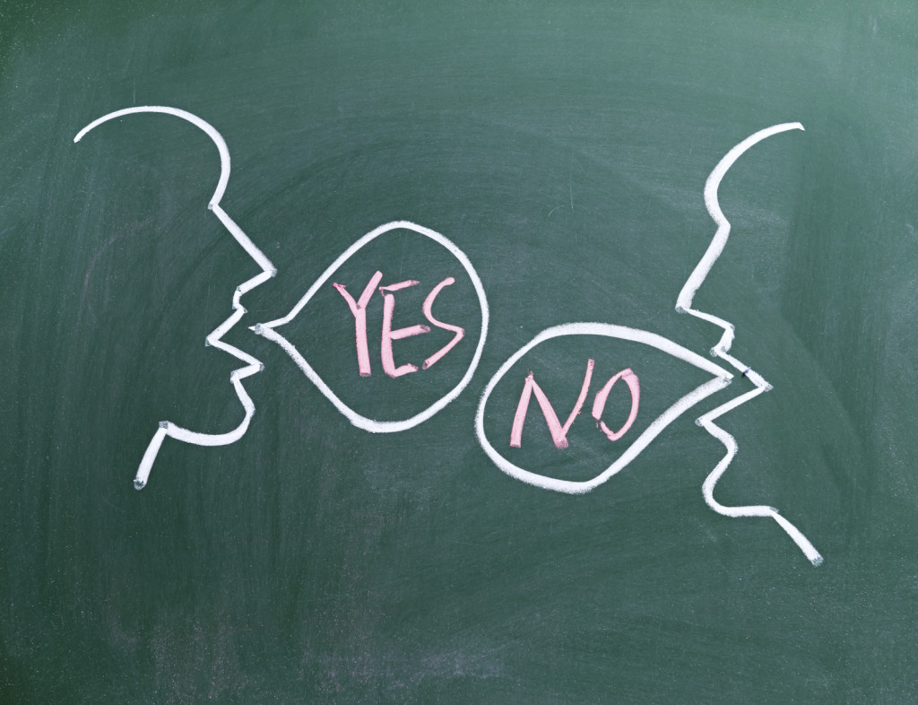 Two faces on blackboard; one saying no and the other one yes