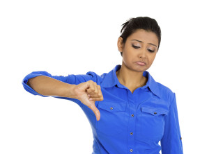 A person in a blue button-up shirt, giving a thumbs down