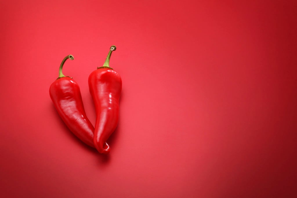 Two chili peppers against a red background