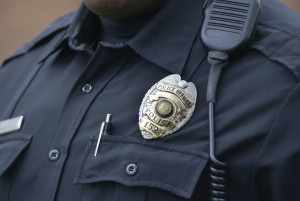 Close-up of a police officer's chest, showing a badge and a walkie talkie