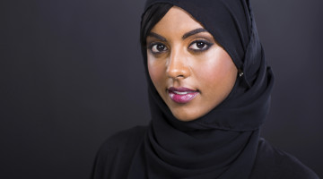 A person wearing black against a gray background