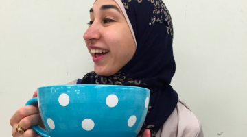 The author, looking away, holding a large, blue, polka-dotted teacup