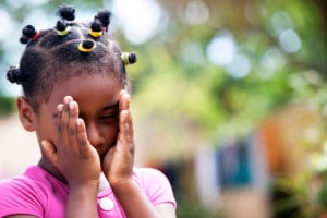 A small child, covering their eyes