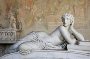 The image features a statue of a person lounging on their side, their face resting on their hand, looking off into the distance.