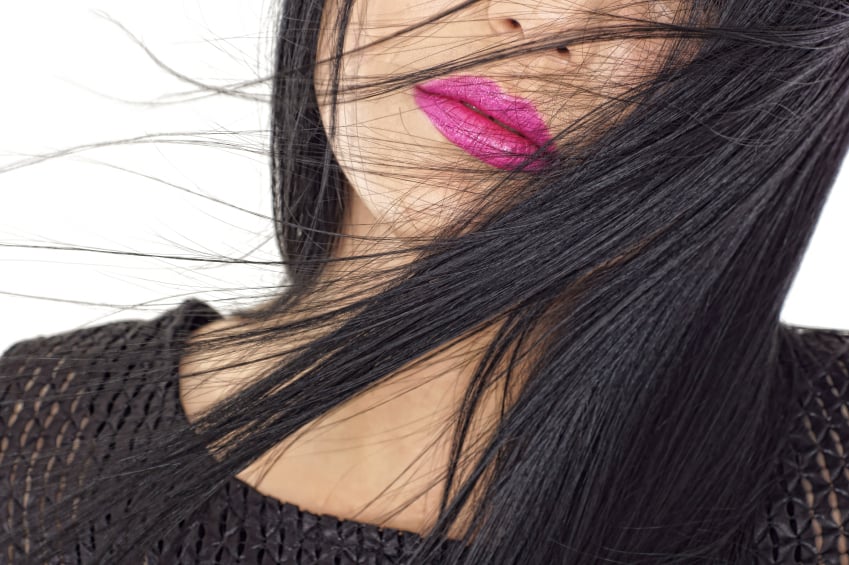 Closeup of a person's face, with long hair and bright pink lipstick.