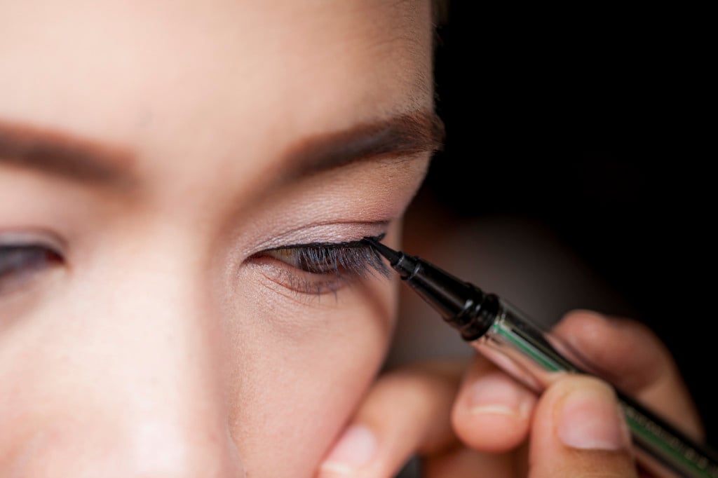 Closeup of a person applying eyeliner.