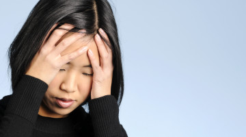 A person, appearing exasperated, holds their hands to their forehead.