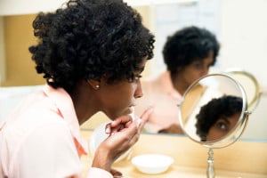A person sits in front of a mirror, getting ready to put a contact lens on their eye.